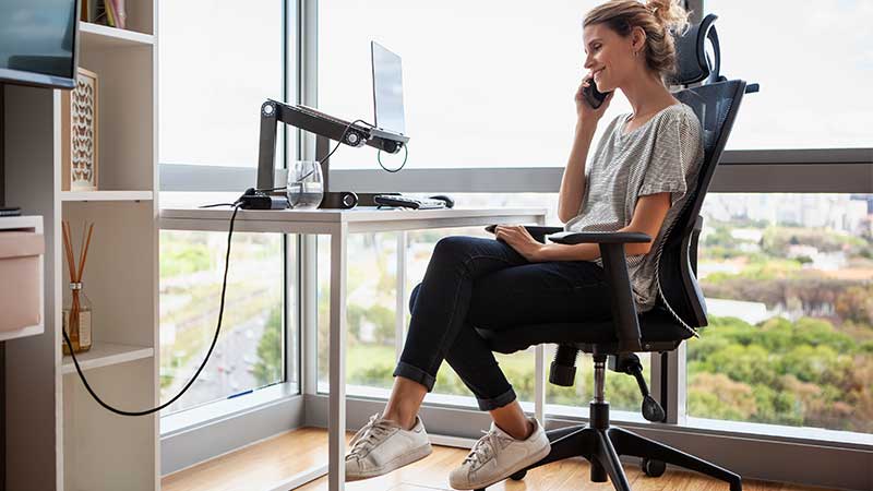 senhora sentada numa cadeira de escritório a falar ao telemóvel em frente a um computador